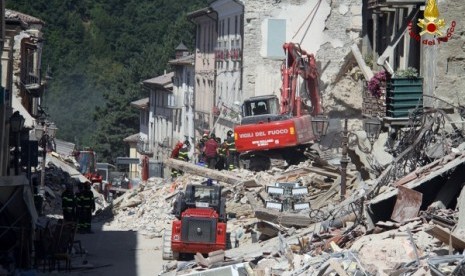 Petugas penyelamat bekerja di sebuah rumah ambruk setelah gempa di Amatrice, Italia Tengah, Jumat (26/8).