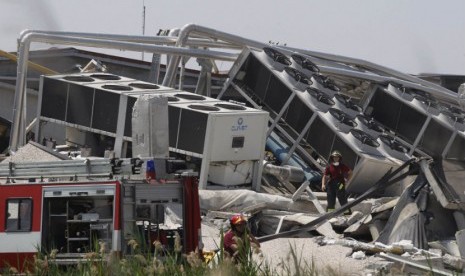  Petugas penyelamat berjalan diatas reruntuhan bangunan akibat gempa bumi yang terjadi di Medolla, Italia, Selasa (29/5). (Giorgio Benvenuti/Reuters) 