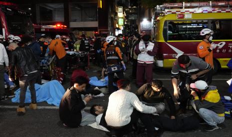 Petugas penyelamat dan petugas pemadam kebakaran berusaha membantu orang-orang yang terluka di dekat lokasi lonjakan massa di Seoul, Korea Selatan, Ahad, 30 Oktober 2022. Sedikitnya 146 orang tewas dan 100 lainnya luka-luka saat tertimpa massa yang mendorong. maju di jalan sempit selama perayaan Halloween di ibukota Seoul kata pejabat. 