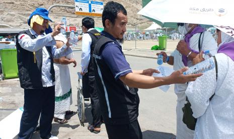 Petugas penyelenggara ibadah haji PPIH Arab Saudi bidang kesehatan terlihat sedang membagikan minuman kepada jamaah haji Indonesia di Mina, Arab Saudi. Hari ini merupakan agenda jamaah haji melempar Jumrah Aqabah, Sabtu (9/7/2022). Begini Cara Petugas Menyemangati Jamaah Haji Melempar Jumrah