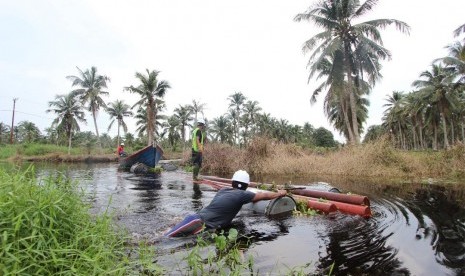 Petugas PLN bersama warga desa bergotong royong mengangkat perlengkapan seperti tiang, kabel dan material listrik.