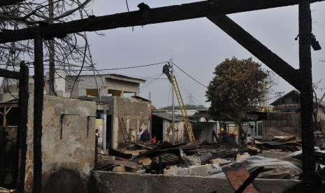 Petugas PLN memperbaiki kabel listrik yang terdampak kebakaran rumah penduduk di Jalan Swadaya, Cakung, Jakarta Timur, Senin (29/8/2022). Kebakaran yang terjadi pada pukul 03.24 WIB menghanguskan 40 rumah warga dan penyebab kebakaran akibat korsleting listrik. 