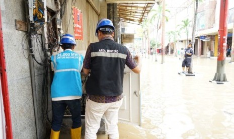 Petugas PLN tengah memeriksa gardu distribusi di lingkungan permukiman warga. Pihak PLN masih akan mematikan sementara aliran listrik ke rumah-rumah warga terdampak banjir.  