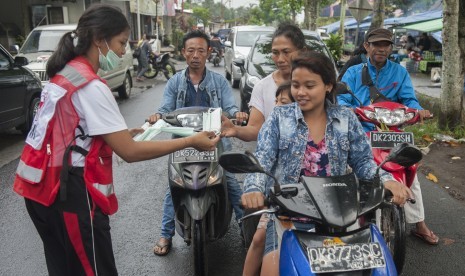 Relawan membagikan masker kepada pengendara di Pasar Desa Menanga yaitu kawasan rawan bencana Gunung Agung, Karangasem, Bali.