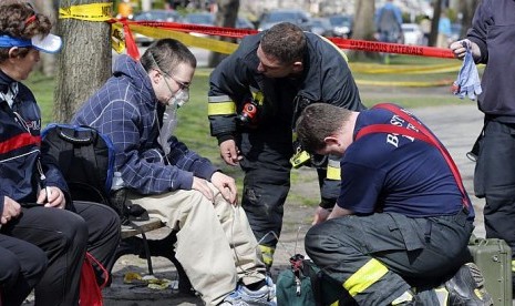 Petugas PMK memastikan kondisi seorang korban selamat dalam insiden ledakan bom di dekat garis finis Maraton Boston 2013, Senin 15 April, 2013