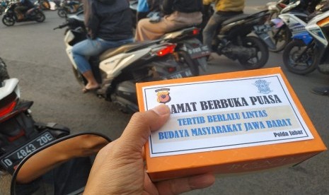 Petugas Polantas Polda Jabar membagikan takjil di simpang Jl Terusan Buah Batu-Sukarno Hatta Bandung, Jumat (17/5).