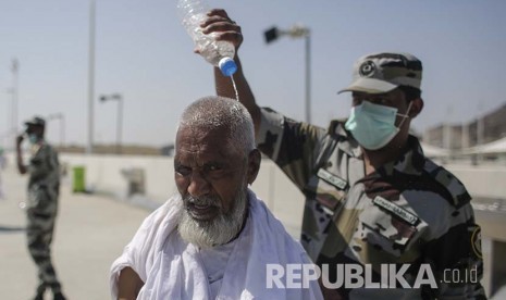 Ilustrasi. Petugas polisi Arab Saudi menyiramkan air ke kepala seorang jamaah haji untuk mengurangi sengatan panas matahari di Jamarat, Senin (12/9). Gelombang Panas Landa Arab Saudi, Suhu Makkah dan Madinah 49 Derajat Celsius