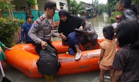 Petugas Polisi dan BPBD Kota Tangerang mengevakuasi warga yang terendam banjir di perumahan Total Persada, Tangerang, Banten, Senin (14/11). 