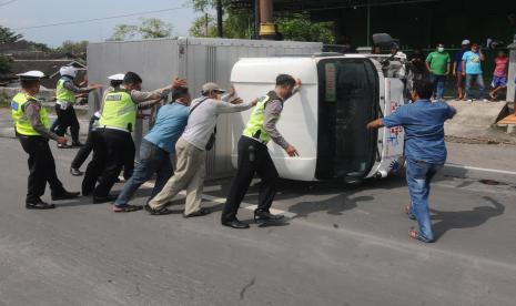 Petugas polisi dibantu warga mendorong truk yang terbalik karena kecelakaan di Jalan Solo-Jogja perbatasan Kabupaten Sukoharjo, Boyolali dan Klaten, Jawa Tengah, Sabtu (2/4/2022). Kecelakaan yang melibatkan tiga truk dan satu mobil itu masih dalam proses penyelidikan pihak polisi.