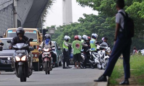 Petugas Polisi Lalu Lintas memberhentikan kendaraan roda dua di Jalan Basuki Rahmat, Jakarta Timur, Rabu (7/5).