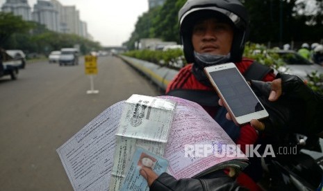 Petugas polisi melakukan penindakan terhadap pelanggar lalu lintas dengan mengunakan sistem E-Tilang saat razia kendaraan bermotor di Kawasan Kemayoran, Jakarta, Rabu (11/1). 