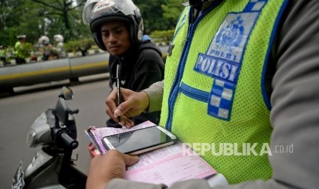 Petugas polisi melakukan penindakan terhadap pelanggar lalu lintas dengan mengunakan sistem E-Tilang saat razia kendaraan bermotor di Kawasan Kemayoran, Jakarta, Rabu (11/1).