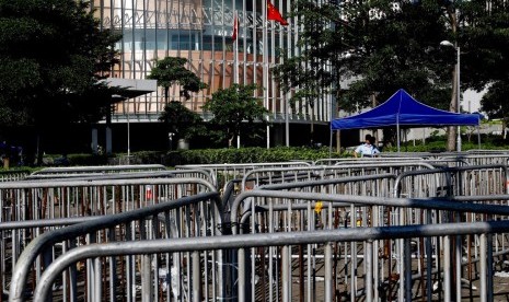 Petugas polisi melihat ke arah penghalang di sekitar gedung dewan di Hong Kong, Jumat (14/6). Suasana kembali tenang di Hong Kong setelah berhari-hari digelar protes oleh aktivis HAM dan mahsiswa menentang UU yang membiarkan tersangka diadili di pengadilan daratan Cina. 