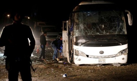 Petugas polisi memeriksa bus yang terkena ledakan bom di dekat Piramida Giza, Kairo, Jumat (28/12)