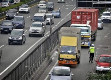 Petugas Polisi mengatur lalu lintas truk di pintu masuk Tol, jalan S. Parman, Kebon Jeruk, Jakarta Barat.