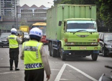 Petugas Polisi mengatur lalu lintas truk di pintu masuk Tol, jalan S. Parman, Kebon Jeruk, Jakarta Barat.