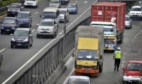 Petugas Polisi mengatur lalu lintas truk di pintu masuk Tol, jalan S. Parman, Kebon Jeruk, Jakarta Barat.