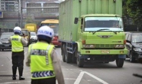 Petugas Polisi mengatur lalu lintas truk di pintu masuk Tol, jalan S. Parman, Kebon Jeruk, Jakarta Barat.