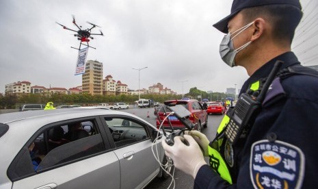 China catat 76.288 kasus Corona dengan 2.345 kematian. Foto: Petugas polisi mengoperasikan drone yang membawa QR code dekat pintu tol di Shenzen, Guangdong, China. Penggunaan QR code membantu polisi mendaftar kendaraan yang kembali ke Shenzen tanpa harus langsung kontak dengan pengemudi hingga meminimalisir penyebaran corona.