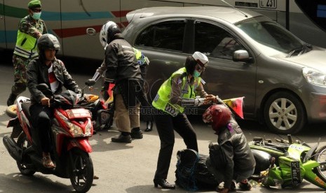  Petugas Polisi menolong pengendara motor yang terjatuh di Jalan Cagak Nagreg, Kabupaten Bandung, Ahad(27/7). (foto : Septianjar Muharam)