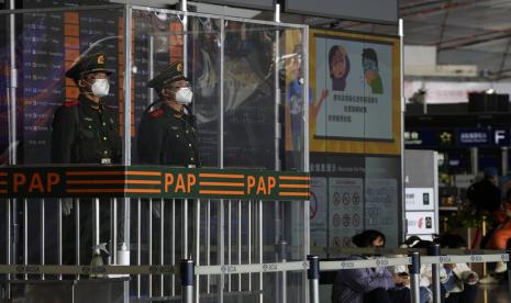 Petugas polisi paramiliter China yang mengenakan masker berjaga di pos mereka di dekat pajangan peringatan agar tidak menyembunyikan gejala COVID-19 di terminal bandara Capital di Beijing, Selasa, 13 Desember 2022. Beberapa universitas China mengatakan mereka akan mengizinkan siswa menyelesaikan semester dari rumah dengan harapan dapat mengurangi potensi wabah COVID-19 yang lebih besar selama kesibukan perjalanan Tahun Baru Imlek di bulan Januari.