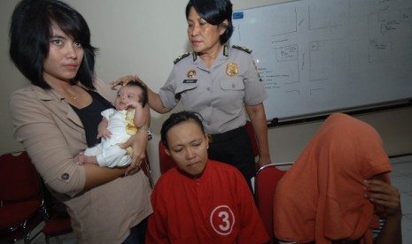 Petugas polisi wanita (polwan) menunjukkan sejumlah tersangka dan bayi ketika ungkap kasus penjualan bayi di Mapolrestabes Surabaya, Jatim, Minggu (28/7).