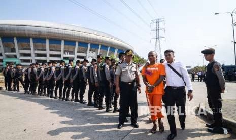 Petugas Polrestabes Bandung membawa seorang tersangka saat menggelar rekonstruksi pengeroyokan yang dilakukan oleh oknum bobotoh terhadap seorang suporter Persija, Haringga Sirla, di Stadion Gelora Bandung Lautan Api (GBLA), Bandung, Jawa Barat, Rabu (26/9). 