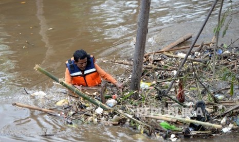 Petugas PPSU membersihkan sampah yang menyangkut di kaki jembatan di Sungai Banjir Kanal Barat, Jakarta Pusat, Senin (6/2).