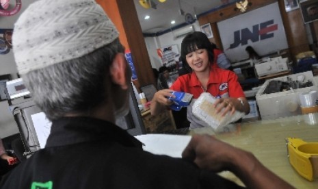 Petugas PT. JNE melayani pengguna jasa di kantor pusat JNE, Tomang, Jakarta, Senin (21/3).