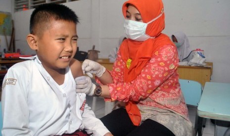 Petugas Puskesmas Sindangbarang Bogor memberikan imunisasi campak Rubella kepada siswa di SD Insan Kamil, Kota Bogor, Jawa Barat, Rabu (9/8). 