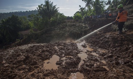 Petugas SAR menyemprotkan air ke material longsor guna mempermudah pencarian korban longsor yang diduga tertimbun tanah di Caok, Loano, Purworejo, Jawa Tengah, Rabu (22/6).