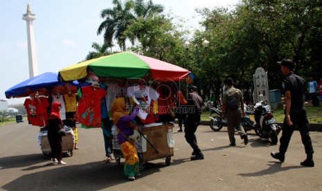   Petugas Satpol PP bersama Petugas UPT Monas, TNI dan polisi menertibkan para pedagang kaki lima (PKL) di kawasan Tugu Monas, Jakarta Pusat, Rabu (30/7). (Republika/Yasin Habibi)