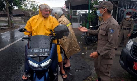 Petugas Satpol PP Kabupaten Badung menghentikan warga negara asing (WNA) yang melanggar protokol kesehatan saat operasi penertiban prokes dalam Pemberlakuan Pembatasan Kegiatan Masyarakat (PPKM) skala mikro di Desa Canggu, Badung, Bali, Jumat (25/6/2021). Tim satgas gabungan menindak sebanyak 18 orang WNA yang berasal dari berbagai negara tersebut untuk memberikan efek jera agar menerapkan protokol kesehatan dalam upaya pencegahan penyebaran varian baru COVID-19 di kawasan pariwisata itu.