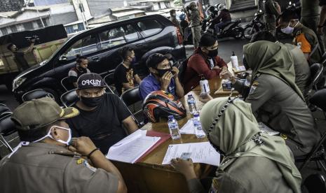 Petugas Satpol PP melakukan pendataan terhadap pengendara sepeda motor dan sopir yang tidak menggunakan masker saat berkendara dalam Operasi Tertib Masker di kawasan Kampung Melayu, Jakarta, Senin (7/9/2020). Satpol PP DKI Jakarta mencatat jumlah denda akumulasi pelanggaran ketentuan Pembatasan Sosial Berskala Besar atau PSBB transisi mulai 22 Mei hingga 31 Agustus 2020 mencapai Rp4 miliar dengan denda perorangan pelanggar penggunaan masker menjadi yang paling besar yaitu sebanyak Rp1,94 miliar.