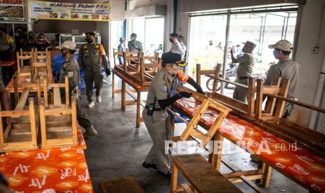 Petugas Satpol PP melakukan penertiban area kantin yang menyediakan makan di tempat saat razia penerapan Pembatasan Sosial Berskala Besar (PSBB)  di kawasan Cakung, Jakarta, Selasa (15/9/2020). Razia tersebut untuk memastikan masyarakat mematuhi dan tertib terhadap aturan yang berlaku selama PSBB  DKI Jakarta. 