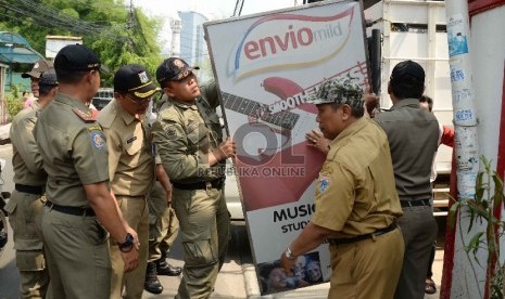  Petugas satpol pp melakukan penurunan reklame rokok di Kawasan Tegalparang, Jakarta Selatan, Rabu (18/11).