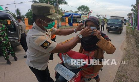 Petugas satpol PP membantu memasangkan masker kepada pengendara roda dua yang akan menuju ke Desa Berkah di Pos Penyekatan Sungai Bahar, Muarojambi, Jambi, Kamis (12/8/2021). Penyekatan oleh tim gabungan Satgas COVID-19 Kabupaten Muarojambi yang di antaranya mensyaratkan kepemilikan surat atau kartu vaksin dan hasil tes usap negatif COVID-19 bagi warga luar daerah itu bertujuan mengendalikan mobilitas warga untuk mengantisipasi penyebaran COVID-19.