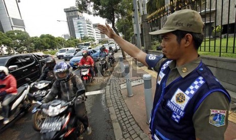  Petugas Satpol PP membantu mengatur lalu lintas  di sekitar Bundaran Patung Kuda, Jakarta Pusat, Senin (4/2).   (Republika/Adhi Wicaksono)