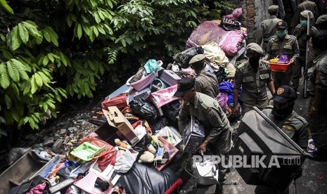 Petugas Satpol PP memindahkan  barang milik warga saat penggusuran permukiman Tamansari, Kota Bandung, Kamis (12/12). 