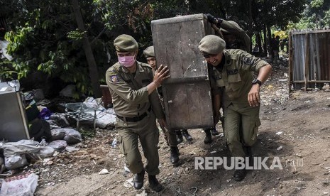 Petugas Satpol PP memindahkan  barang milik warga saat penggusuran permukiman Tamansari, Kota Bandung, Kamis (12/12). 