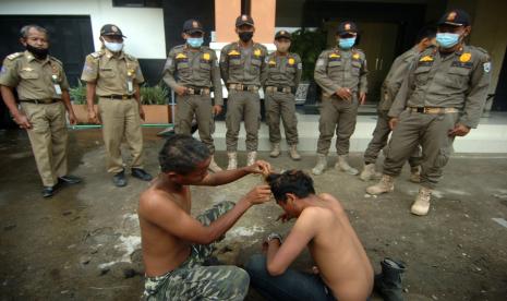 Petugas Satpol PP memberi sanksi anak punk untuk mencukur rambut saat terjaring razia. (ilustrasi)