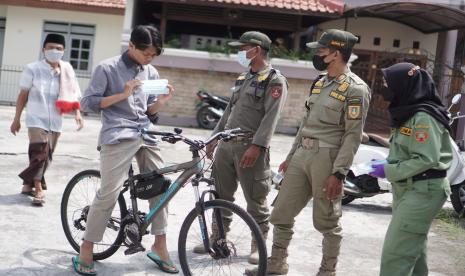 Petugas Satpol PP memberikan masker kepada warga yang tidak mengenakan masker saat akan melaksanakan salat Jumat di Masjid An Nur, Sumber, Solo, Jawa Tengah, Jumat (21/5/2021). Satuan Gugus Tugas (Satgas) COVID-19 kelurahan setempat memperketat protokol kesehatan pelaksanaan shalat Jumat di masjid tersebut setelah ditemukan klaster buka bersama dengan total 42 orang terkonfirmasi positif COVID-19. 