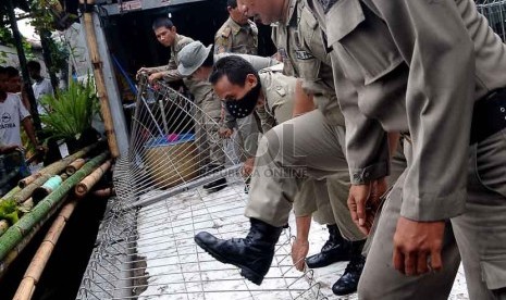  Petugas Satpol PP membongkar bangunan yang berdiri di atas saluran air di jalan Baladewa, Tanah Tinggi, Jakarta Pusat, Selasa (3/12).     (Republika/Prayogi)