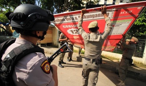 Petugas Satpol PP membongkar paksa Alat Peraga Kampanye (APK) di jalan protokol Pusat Kota Lhokseumawe, Aceh, Senin (10/12).