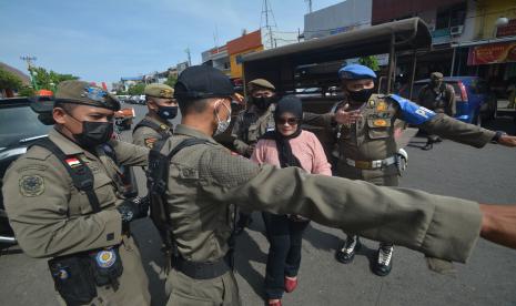 Petugas Satpol PP mengamankan seorang warga yang tidak menggunakan masker di Pasar Raya, Padang, Sumatera Barat, Rabu (28/4/2021). Razia gabungan tersebut untuk mengamankan warga yang tidak menggunakan masker di luar rumah terkait Pemberlakuan Pembatasan Kegiatan Masyarakat (PPKM) skala mikro di provinsi itu dan akan diproses sesuai Perda nomor 6 tahun 2020 tentang Adaptasi Kebiasaan Baru.