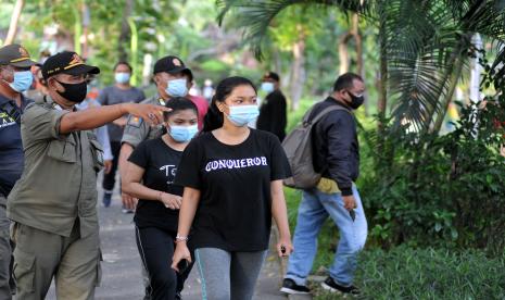 Petugas Satpol PP mengarahkan warga di Taman Kota Lumintang, Denpasar, Bali, Senin (21/6/2021).