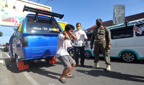 Petugas Satpol PP menghukum seorang supir angkot dengan squat jump karena tidak menggunakan masker di Pasar Raya, Padang, Sumatera Barat, Jumat (15/5/2020). Pemkot Padang memperketat warga masuk ke Pasar Raya selama PSBB tahap kedua, dengan merazia masker dan pengecekan suhu tubuh karena pasar itu merupakan klaster terbanyak yang terdapat kasus positif COVID-19 di Padang.