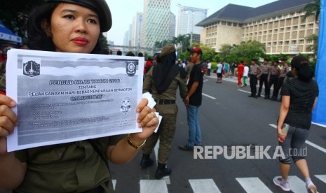 Petugas Satpol PP wanita menyosialisasikan Pergub tentang larangan melakukan kegiatan politik diacara dan tempat berlangsungnya Hari Bebas Kendaraan Bermotor atau Car Free Day (CFD) di Jakarta, Ahad (6/5).