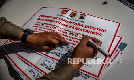 Petugas Satuan Pamong Praja (Satpol PP) menyiapkan lembar segel tempat usaha yang melanggar aturan saat giat penerapan PPKM Darurat di Kota Semarang, Jawa Tengah, Senin (5/7/2021). Pada hari ketiga PPKM Darurat Jawa-Bali, personel gabungan TNI-Polri dan Satpol PP berkeliling Kota Semarang guna menegakkan pembatasan kegiatan masyarakat dengan imbauan tentang penerapan protokol kesehatan serta menyegel tempat usaha yang melanggar aturan sebagai upaya menekan lonjakan kasus COVID-19. 