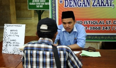 Petugas sedang berbicara dengan warga pada tempat penerimaan zakat di masjid Istiqlal, Rabu (16/7).